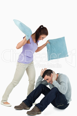 Young female hitting her boyfriend with pillows