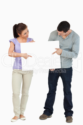 Young couple pointing and looking at sign they are holding