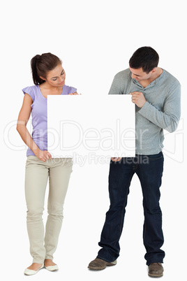 Young couple looking at sign they are holding