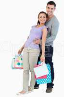 Young male holding his girlfriend with her shopping