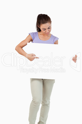 Young female pointing and looking at banner in her hands