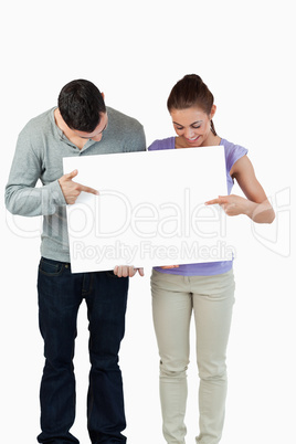 Young couple pointing at banner they are holding