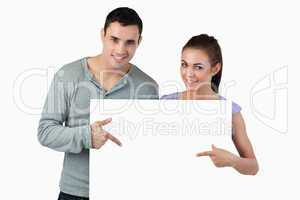 Young couple pointing at banner in front of them