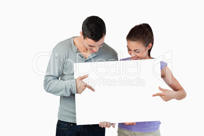 Young couple pointing at banner they are presenting