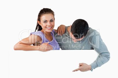 Smiling young female with her boyfriend behind a wall