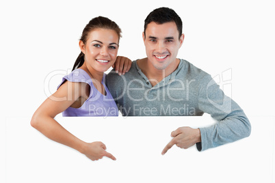 Young couple pointing at advertisement below them
