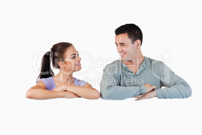 Young couple looking at each other while leaning on a wall
