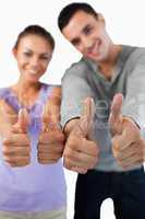 Close up of thumbs up being given by young couple