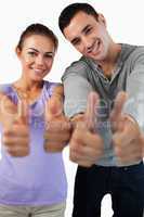 Close up of young couple giving thumbs up