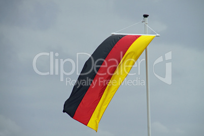 Wehende Deutschland-Fahne vor grauem Himmel