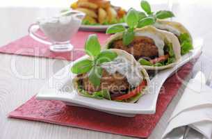 Patty in pita bread with cream sauce and vegetables
