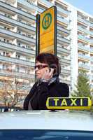Frau steht an der Bushaltestelle und ruft sich ein Taxi