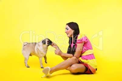 pin-up girl in doll dress feed a dog with cheese