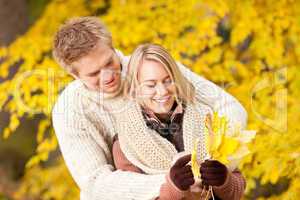 Autumn happy couple holding leaves in  park