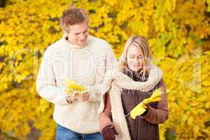 Autumn happy couple holding leaves in park