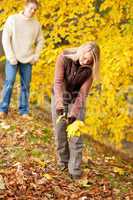 Autumn happy couple picking leaves in park