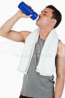 Young man drinking water after training