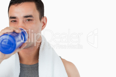 Young male taking a sip of water after training