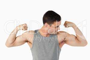 Young man looking at his muscles