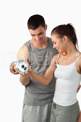 Portrait of a handsome man helping a woman to work out