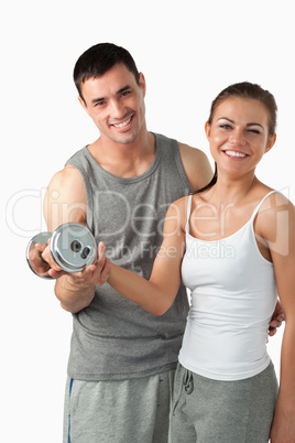 Portrait of a man helping a smiling woman to work out