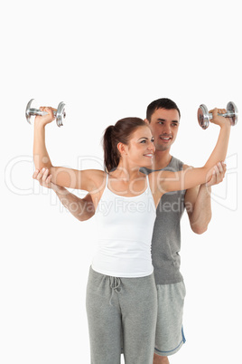 Portrait of a young man helping a gorgeous woman to work out