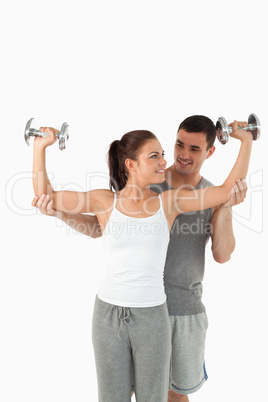 Portrait of a young man helping a smiling woman to work out