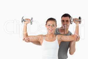 Young man helping a smiling woman to work out