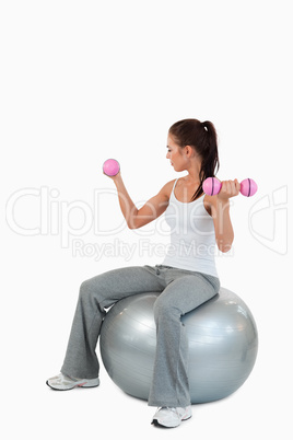 Portrait of a young woman working out with dumbbells and a ball
