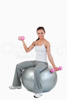 Portrait of a smiling woman working out with dumbbells and a bal