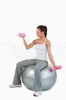 Portrait of a cute woman working out with dumbbells and a ball