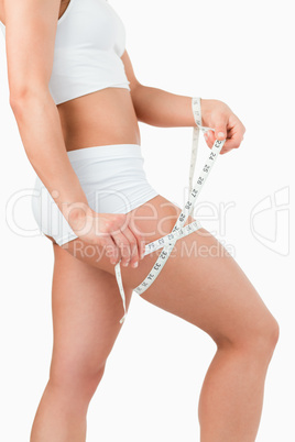 Portrait of a fit woman measuring her thigh