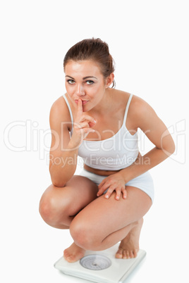 Portrait of a confident woman squatting on scales