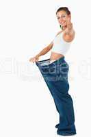Portrait of a fit woman wearing too large pants with the thumb u