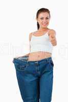 Portrait of a fit woman wearing too large jeans with the thumb u