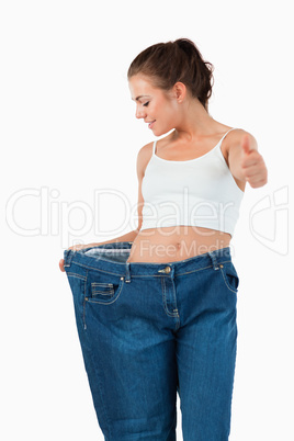 Portrait of a thin woman wearing too large jeans with the thumb