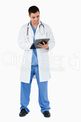 Portrait of a young doctor writing on a clipboard