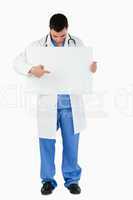 Portrait of a young doctor pointing at a blank panel