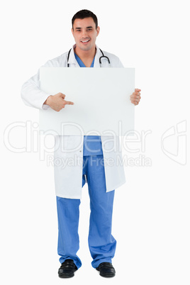 Portrait of a handsome doctor pointing at a blank panel