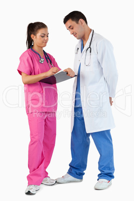 Portrait of a doctor talking while his intern is taking notes