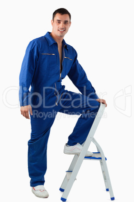 Portrait of a handsome mechanic climbing on a stool