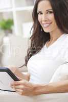 Young Brunette Woman Using Tablet Computer At Home on Sofa