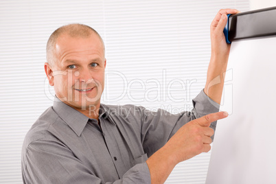 Mature businessman pointing at empty flip chart