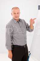 Mature businessman pointing at empty flip chart