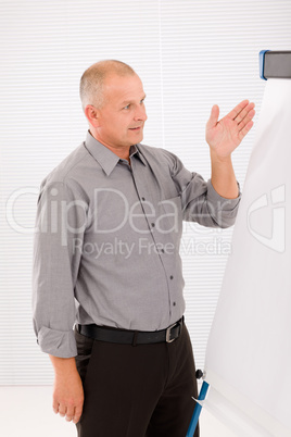 Mature businessman pointing at empty flip chart