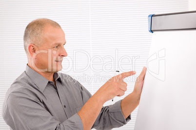 Mature businessman writing at empty flip chart