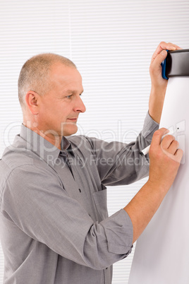 Mature businessman writing at empty flip chart