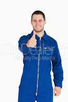 Thumb up given by smiling young mechanic in boiler suit