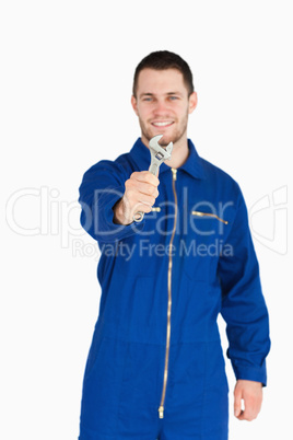 Wrench shown by smiling young mechanic in boiler suit