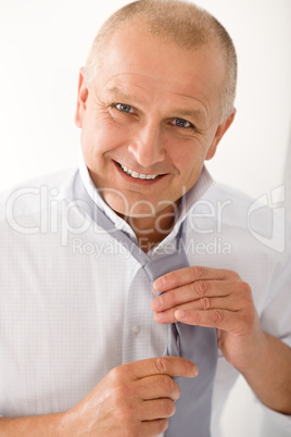 Business mature man smiling tie a tie